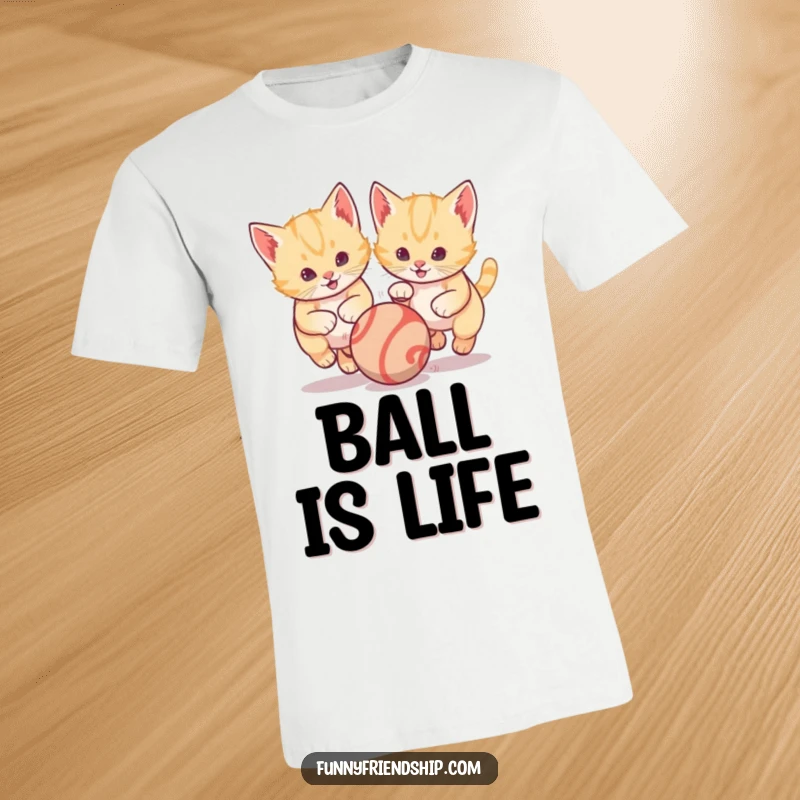 Funny t-shirt featuring two lively kittens enthusiastically chasing a single bouncing ball, illustrating playful energy and shared fun moments.